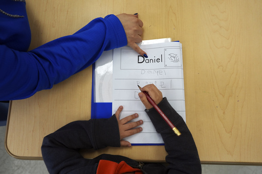 FILE - Easterseals Head Start program teaching assistant Tania Ortiz helps a student practice writing his name, Jan. 29, 2025, in Miami. (AP Photo/Rebecca Blackwell, File)