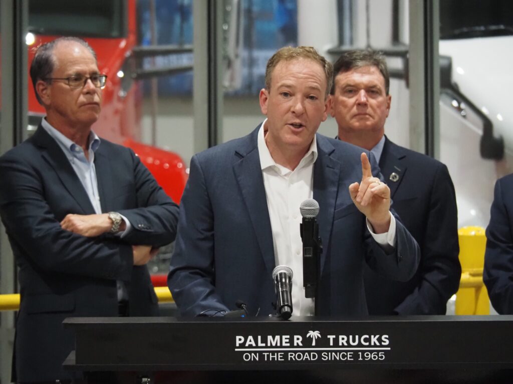 EPA Administrator Lee Zeldin, center, announces his agency's plans for deregulation from an Indianapolis trucking facility on Tuesday, July 29, 2025. At left is Indiana Gov. Mike Braun and at right is Indiana Attorney General Todd Rokita.  (Photo by Leslie Bonilla Muñiz/Indiana Capital Chronicle)