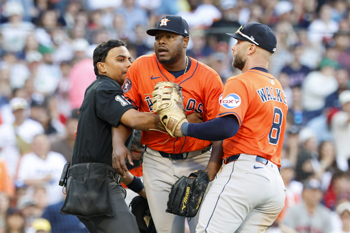 Home plate umpire Gerry Davis, left, and Houston Astros first baseman Christian Walker (8) restrain Astros pitcher Hector Neris, center, at the end of the seventh inning of a baseball game against the Boston Red Sox, Saturday, Aug. 2, 2025, in Boston. (AP Photo/Greg M. Cooper)