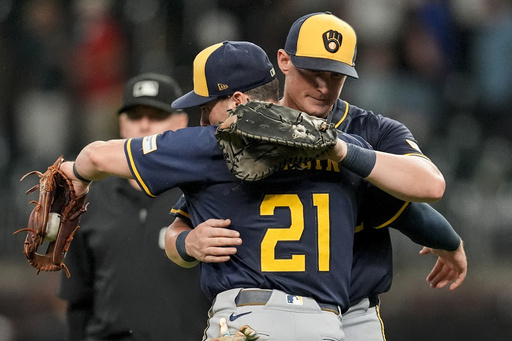 Milwaukee Brewers' Caleb Durbin (21) embraces Andrew Vaughn (28) after a baseball game against the Atlanta Braves, Tuesday, Aug. 5, 2025, in Atlanta. (AP Photo/Mike Stewart)