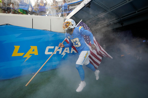 FILE - Los Angeles Chargers wide receiver Keenan Allen carries a United States flag as he is introduced before an NFL football game against the Detroit Lions, Nov. 12, 2023, in Inglewood, Calif. (AP Photo/Gregory Bull, File)