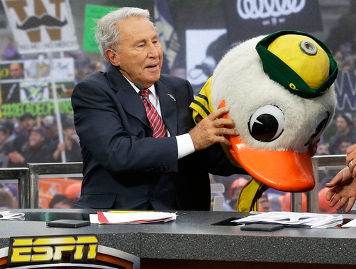 FILE - ESPN College GameDay host Lee Corso puts on the mascot head of the Oregon Ducks, Oct. 12, 2013, during College GameDay's broadcast from Red Square on the University of Washington campus in Seattle. (AP Photo/Ted S. Warren, File)