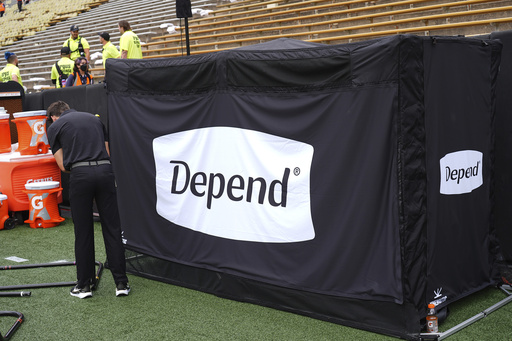 A field worker sets up equipment next to a tent containing a bathroom in the team box on the Colorado sideline before an NCAA college football game against Georgia Tech Friday, Aug. 29, 2025, in Boulder, Colo. (AP Photo/David Zalubowski)