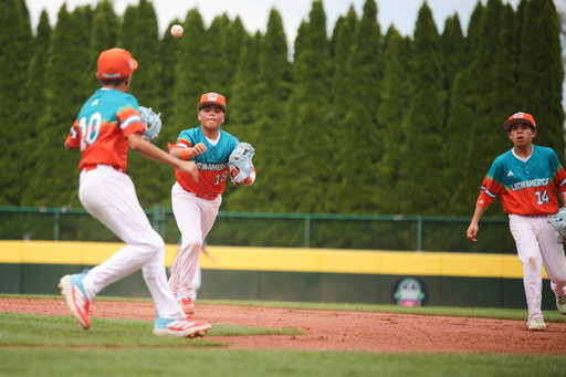 Venezuela's Fabricio Perdomo Canelon (18) tosses a ground ball to teammate Juan Reyes (10) during the sixth inning of a baseball game against Puerto Rico at the Little League World Series Wednesday, Aug. 13, 2025, in South Williamsport, Pa. (AP Photo/Jared Freed)