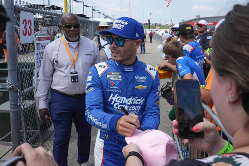 Driver Kyle Larson, center, gives autographs to fans prior to a NASCAR Cup Series auto race, Sunday, Aug. 3, 2025, at Iowa Speedway in Newton, Iowa. (AP Photo/Bryon Houlgrave)