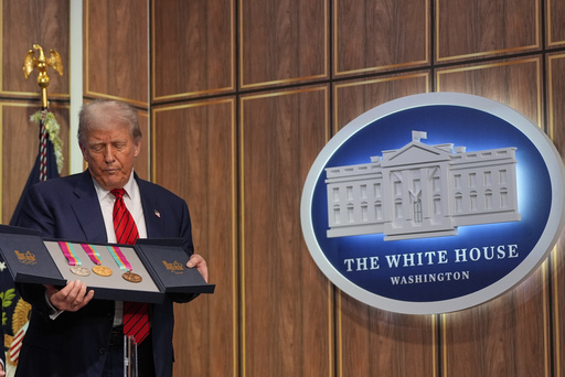President Donald Trump holds a full set of medals from the 1984 Olympics in Los Angeles, during an event regarding the 2028 Los Angeles Olympic Games, in the South Court Auditorium of the Eisenhower Executive Office Building on the White House campus, Tuesday, Aug. 5, 2025, in Washington. (AP Photo/Julia Demaree Nikhinson)