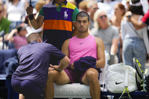 A trainer works on Carlos Alcaraz, of Spain, during a medical timeout in the second set against Luciano Darderi, of Italy, during the third round of the U.S. Open tennis championships, Friday, Aug. 29, 2025, in New York. (AP Photo/Yuki Iwamura)
