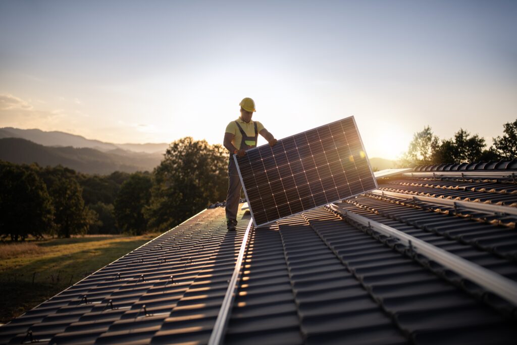 A worker installs solar panels on a roof. (Photo by Getty Images)