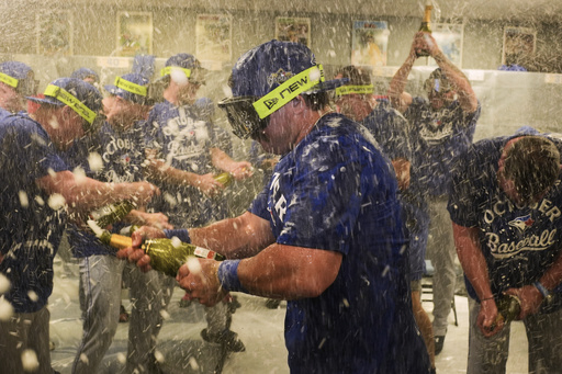 Toronto Blue Jays' Davis Schneider, center, celebrates with teammates in the clubhouse after their baseball game against the Kansas City Royals, Sunday, Sept. 21, 2025, in Kansas City, Mo. (AP Photo/Charlie Riedel)