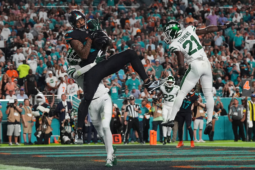 Miami Dolphins tight end Darren Waller (83) catches a touchdown pass as New York Jets' Sauce Gardner, rear, and Brandon Stephens (21) defend in the first half of an NFL football game, Monday, Sept. 29, 2025, in Miami Gardens, Fla. (AP Photo/Marta Lavandier)