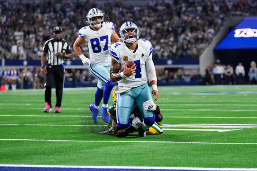 Dallas Cowboys quarterback Dak Prescott (4) is stopped as he carries the ball by Green Bay Packers defensive end Micah Parsons, rear, in overtime of an NFL football game Sunday, Sept. 28, 2025, in Arlington, Texas. (AP Photo/Jeffrey McWhorter)