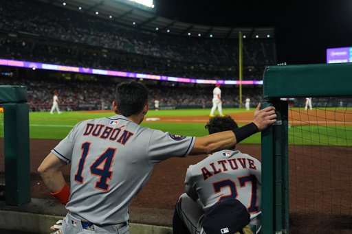 Houston Astros' Mauricio Dubon (14) and Jose Altuve (27) watch from the dugout during the third inning of a baseball game against the Los Angeles Angels Saturday, Sept. 27, 2025, in Anaheim, Calif. (AP Photo/Jae C. Hong)