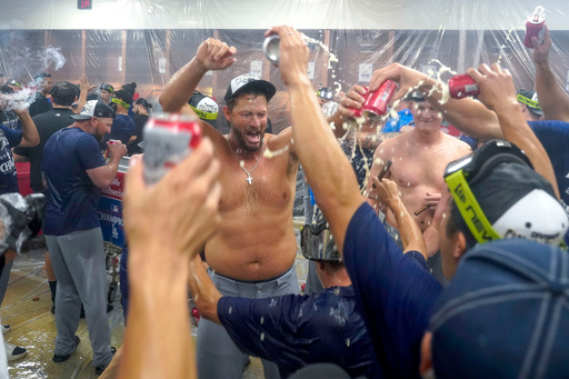 Los Angeles Dodgers pitcher Clayton Kershaw, center, celebrates with his teammates after the Dodgers clinched the National League West title against the Arizona Diamondbacks during a baseball game at Chase Field Thursday, Sept. 25, 2025, in Phoenix. (AP Photo/Darryl Webb)