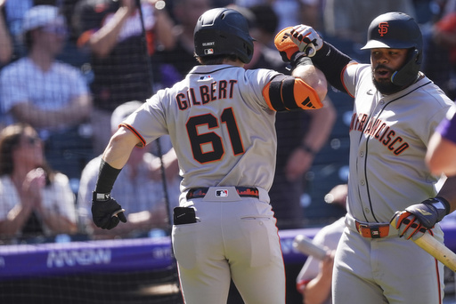 San Francisco Giants' Heliot Ramos, right, congratulates Drew Gilbert(61) who returns to the dugout after hitting a two-run home run off Colorado Rockies starting pitcher Chase Dollander in the third inning of a baseball game Monday, Sept. 1, 2025, in Denver. (AP Photo/David Zalubowski)