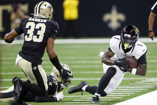 Jacksonville Jaguars running back Travis Etienne Jr. (1) is forced out of bounds by New Orleans Saints safety Jonas Sanker (33) and cornerback Quincy Riley in the first half of an NFL preseason football game in New Orleans, Sunday, Aug. 17, 2025. (AP Photo/Butch Dill)