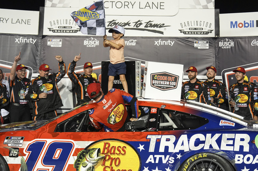Chase Briscoe (19) climbs out of his car as his son Brooks, top, waves the checked flag in Victory Lane after winning a NASCAR Cup Series auto race at Darlington Raceway, Sunday, Aug. 31, 2025, in Darlington, S.C. (AP Photo/Matt Kelley)