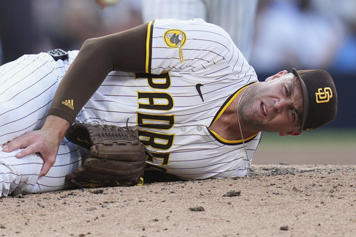 San Diego Padres relief pitcher Jason Adam holds his leg after falling with an injury during the seventh inning of a baseball game against the Baltimore Orioles Monday, Sept. 1, 2025, in San Diego. (AP Photo/Gregory Bull)