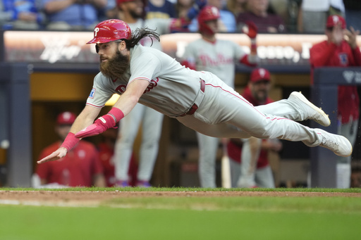 Philadelphia Phillies' Brandon Marsh leaps to score on an RBI double hit by Harrison Bader during the eighth inning of a baseball game against the Milwaukee Brewers, Monday, Sept. 1, 2025, in Milwaukee. (AP Photo/Kayla Wolf)