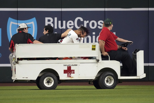 Arizona Diamondbacks' Lourdes Gurriel Jr., third from left, is taken out on a cart after diving for a ball hit by Texas Rangers' Rowdy Tellez in the sixth inning of a baseball game, Monday, Sept. 1, 2025, in Phoenix. (AP Photo/Rick Scuteri)