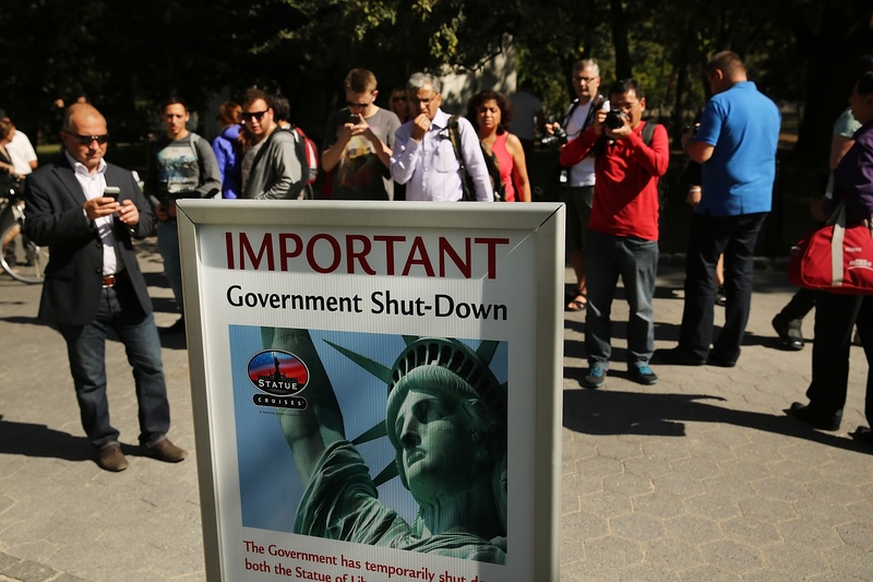 People in New York City look at a sign informing them that the Statue of Liberty is closed on Oct. 1, 2013 due to a government shutdown. (Photo by Spencer Platt/Getty Images)