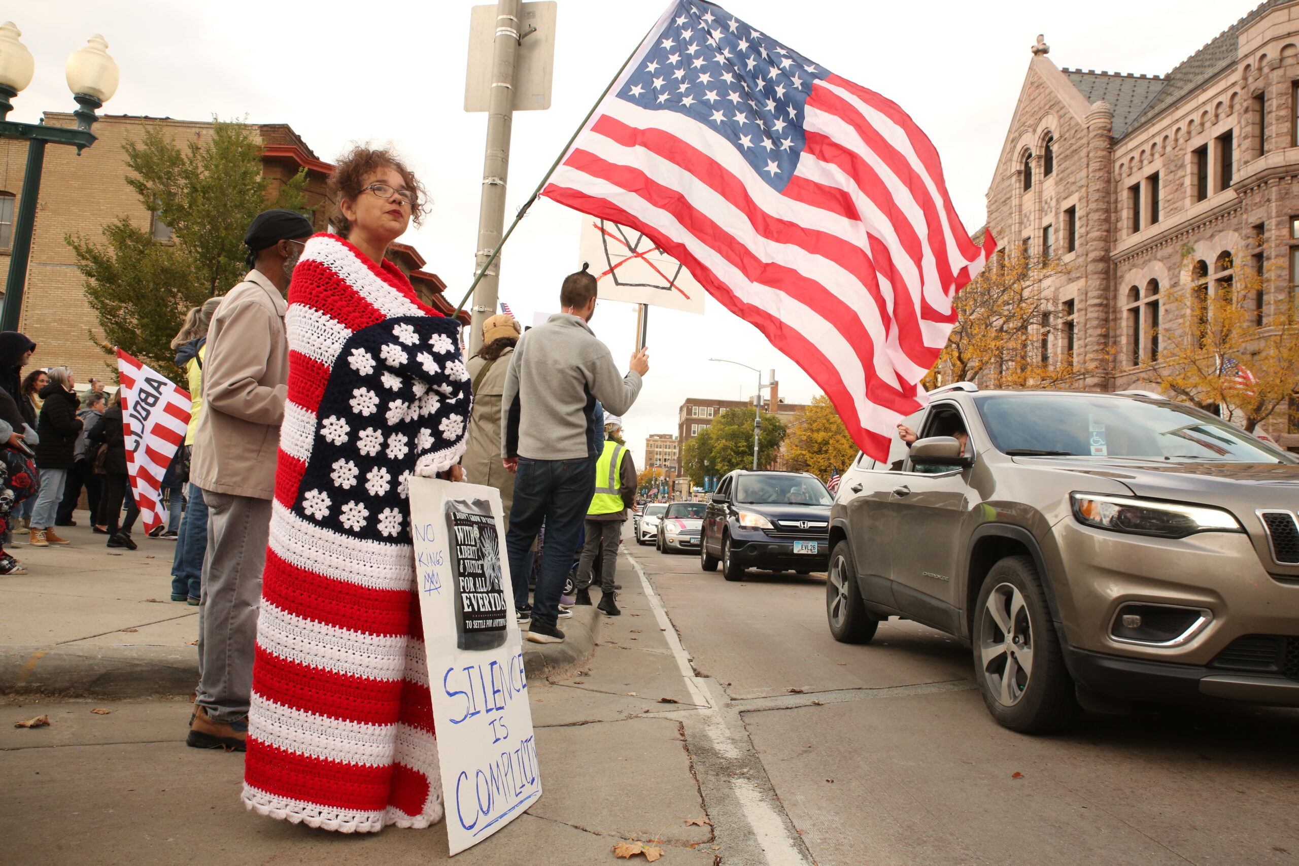 Renee Bostick stands along Phillips Avenue in downtown Sioux Falls on Oct. 18, 2025 for the No Kings protest. (Photo by Makenzie Huber/South Dakota Searchlight)