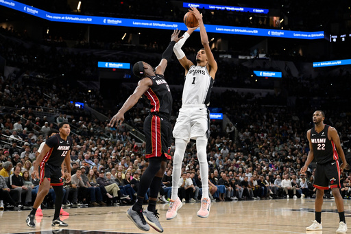 San Antonio Spurs center Victor Wembanyama (1) goes up to shoot against Miami Heat forward Bam Adebayo, center left, during the second half of an NBA basketball game, Thursday, Oct. 30, 2025, in San Antonio. (AP Photo/Darren Abate)