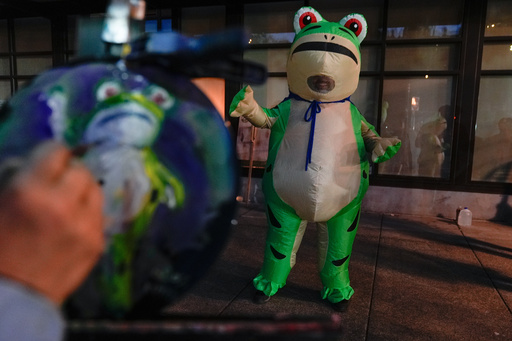 A person paints a portrait of a demonstrator dressed in an inflatable costume outside a United States Immigration and Customs Enforcement (ICE) facility on Tuesday, Oct. 21, 2025, in Portland, Ore. (AP Photo/Jenny Kane)