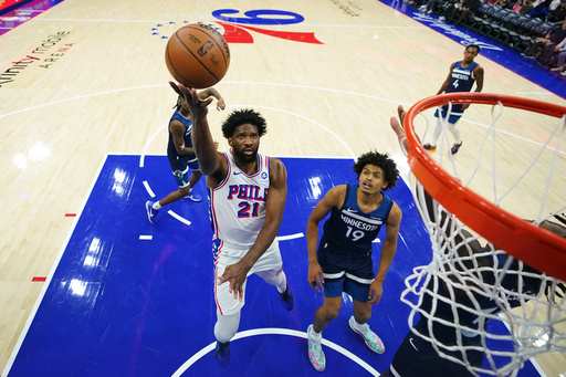 Philadelphia 76ers' Joel Embiid (21) goes up for a shot past Minnesota Timberwolves' Joan Beringer (19) during the first half of an preseason NBA basketball game Friday, Oct. 17, 2025, in Philadelphia. (AP Photo/Matt Slocum)