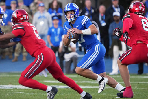 BYU quarterback Bear Bachmeier (47) rolls out to pass as Utah linebacker Lander Barton (8) and Utah safety Tao Johnson (5) defend during the first half of an NCAA college football game Saturday, Oct. 18, 2025, in Provo, Utah. (AP Photo/George Frey)