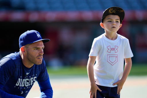 FILE - Los Angeles Dodgers first baseman Freddie Freeman (5) and his son, Charlie Freeman, participate in batting practice before a baseball game against the Los Angeles Angels in Anaheim, Calif., June 21, 2023. (AP Photo/Ashley Landis, File)