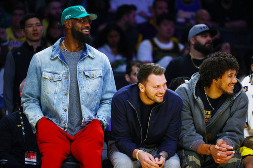 Los Angeles Lakers forward LeBron James (23) and Los Angeles Lakers guard Luka Doncic (77) watch from the bench during the second half of an NBA basketball game against the Portland Trail Blazers, Monday, Oct. 27, 2025, in Los Angeles. (AP Photo/Ethan Swope)