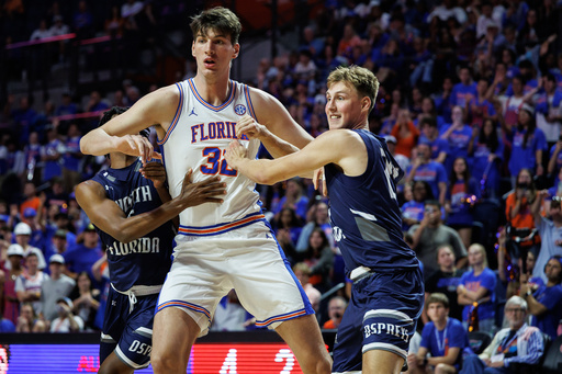 CORRECTS TO SECOND HALF NOT FIRST HALF - North Florida guard Dante Oliver, left and North Florida forward Nestor Dyachok, right, guard against Florida center Olivier Rioux, center, during the second half of an NCAA college basketball game Thursday, Nov. 6, 2025, in Gainesville, Fla. (AP Photo/Chris Watkins)
