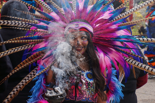A member of an Aztec dance group holds incense during a commemoration of Día de Muertos (Day of the Dead) at El Colegio High School in Minneapolis on Saturday, Nov. 1, 2025. (AP Photo/Giovanna Dell'Orto)
