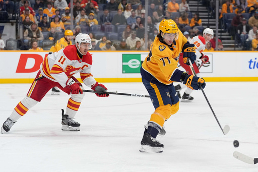 Nashville Predators right wing Luke Evangelista (77) passes the puck past Calgary Flames center Mikael Backlund (11) during the third period of an NHL hockey game Saturday, Nov. 1, 2025, in Nashville, Tenn. (AP Photo/Camden Hall)