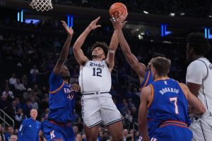 Duke's Cameron Boozer (12) drives past Kansas' Flory Bidunga (40) and Kohl Rosario (7) during the first half of an NCAA college basketball game Tuesday, Nov. 18, 2025, in New York. (AP Photo/Frank Franklin II)
