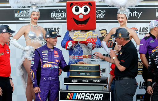 Ryan Growney, center right, general manager of the South Point Hotel and Casino, presents the trophy to Denny Hamlin, center left, in Victory Lane after Hamlin won a NASCAR Cup Series auto race Sunday, Oct. 12, 2025, in Las Vegas. (AP Photo/Steve Marcus)