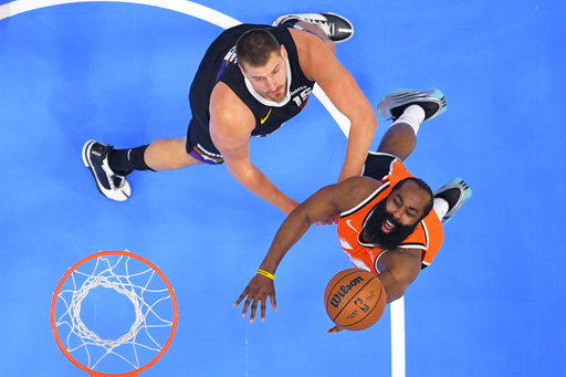 Los Angeles Clippers guard James Harden, right, shoots as Denver Nuggets center Nikola Jokic defends during the first half of an NBA basketball game Wednesday, Nov. 12, 2025, in Inglewood, Calif. (AP Photo/Mark J. Terrill)
