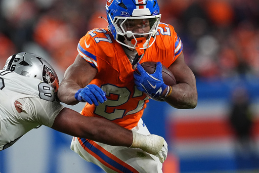 Denver Broncos running back J.K. Dobbins, right, runs for a first-down as Las Vegas Raiders defensive tackle Jonah Laulu makes the stop in the second half of after an NFL football game Thursday, Nov. 6, 2025, in Denver. (AP Photo/David Zalubowski)