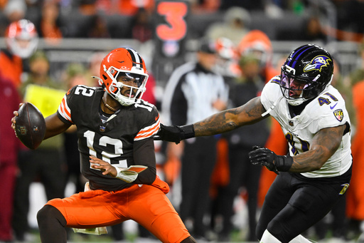 Cleveland Browns quarterback Shedeur Sanders (12) is pressured out of the pocket by Baltimore Ravens' Dre'Mont Jones (41) in the second half of an NFL football game in Cleveland, Sunday, Nov. 16, 2025. (AP Photo/David Richard)