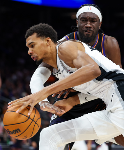 Phoenix Suns center Mark Williams (15) defends as San Antonio Spurs forward Victor Wembanyama (1) dribbles into the paint during the second half of an NBA basketball game, Sunday, Nov. 2, 2025, in Phoenix. (AP Photo/Mike Christy)