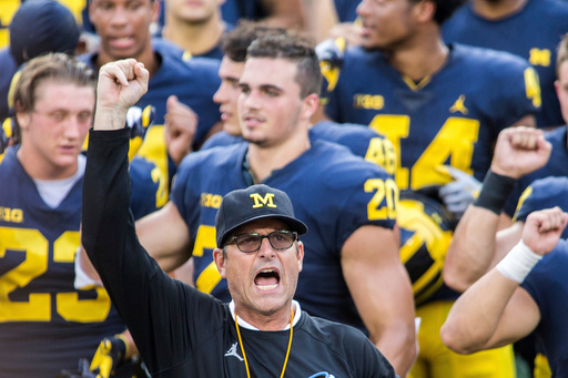 FILE - In this Aug. 26, 2018, file photo, Michigan head coach Jim Harbaugh leads his players and fans in singing "Hail to the Victors" after a practice session by the NCAA college football team at Michigan Stadium in Ann Arbor, Mich..(AP Photo/Tony Ding, File)
