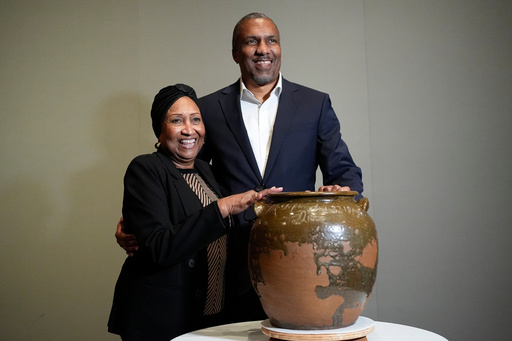 Pauline Baker and her son, Yaba Baker, pose with one of the pots created by their enslaved ancestor, David Drake, at the Museum of Fine Arts, Monday, Nov. 10, 2025, in Boston. (AP Photo/Robert F. Bukaty)