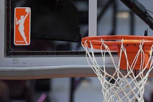 FILE - The WNBA logo is seen near a hoop before an WNBA basketball game at Mohegan Sun Arena, May 14, 2019, in Uncasville, Conn. (AP Photo/Jessica Hill, File)